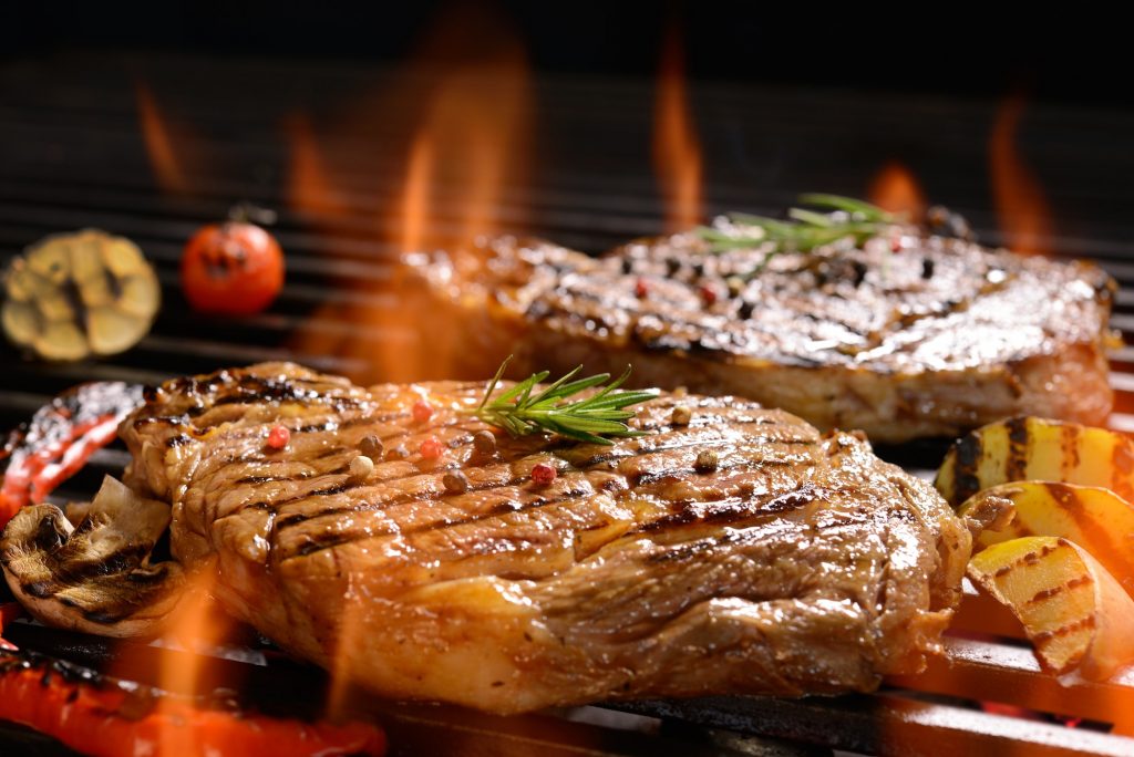 Grilled pork steak with vegetable on the flaming grill